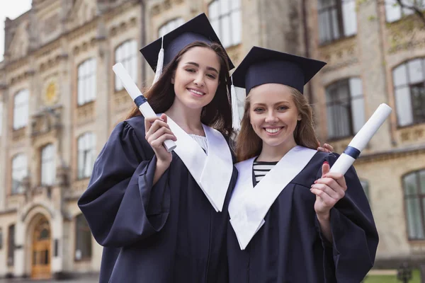Két szép diplomások viselése végzősök — Stock Fotó