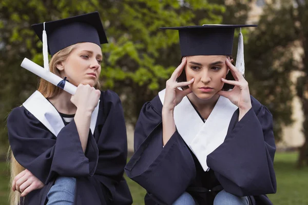 Sötét hajú diák birtoklás fejfájás, miután aggasztó a diplomaszerzés nap — Stock Fotó