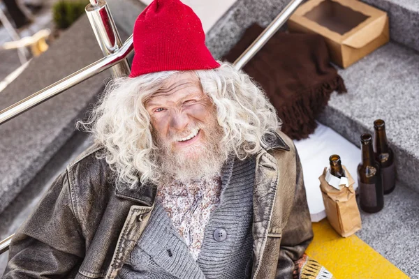 Merdivenlerde oturan olumlu evsiz adam