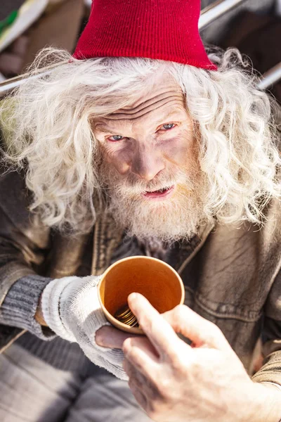 Pobre hombre infeliz sosteniendo una copa con monedas — Foto de Stock