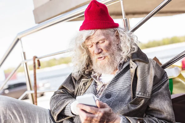 Hombre de edad agradable mirando la pantalla del teléfono inteligente — Foto de Stock