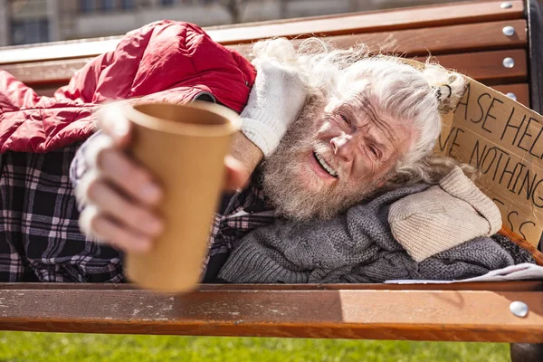 Депрессивный пожилой мужчина держит пластиковую чашку — стоковое фото