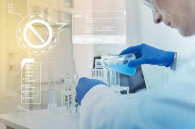 Dikkatli bilim adamı bir laboratuarda olurken mavi sıvı test tüpleri dökme