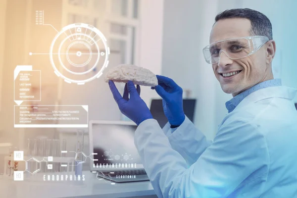 Cientista feliz olhando feliz enquanto segurando um modelo de cérebro realista — Fotografia de Stock