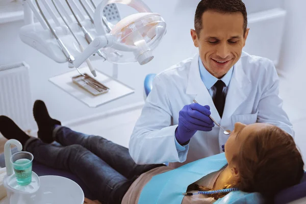 Positive delighted dentist sitting near patient — Stock Photo, Image
