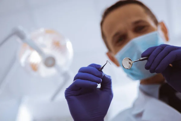 Сфокусированное фото на стоматологе, который смотрит в камеру — стоковое фото