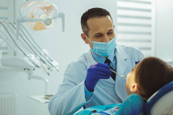 Компетентный стоматолог смотрит на своего пациента
