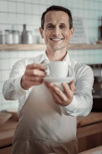 Glad brunett visar cup med drink — Stockfoto