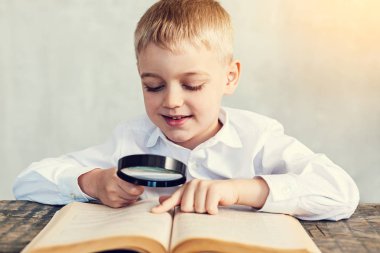 Mutlu çocuk okuma sırasında bir büyüteç tutarak