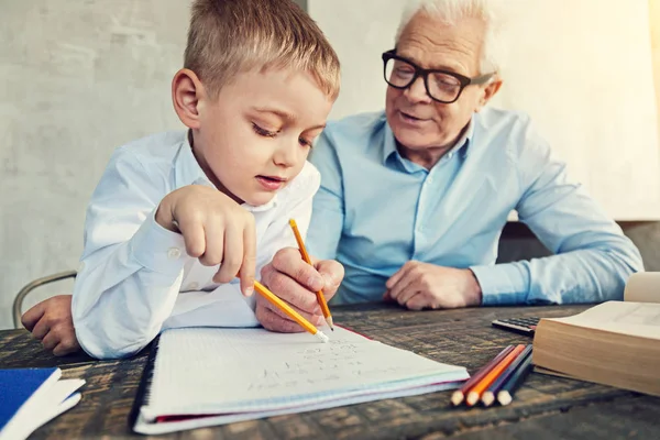 Élève attentif faisant ses devoirs avec son grand-père — Photo