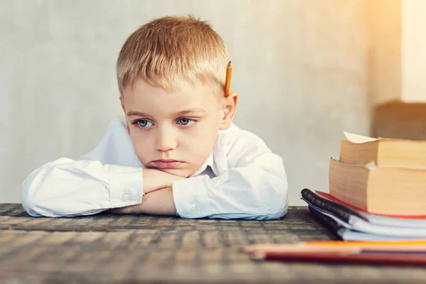 Smutný malý chlapec sedí u stolu — Stock fotografie