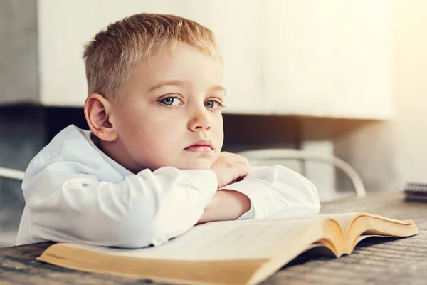 Triste petit garçon assis avec un livre — Photo