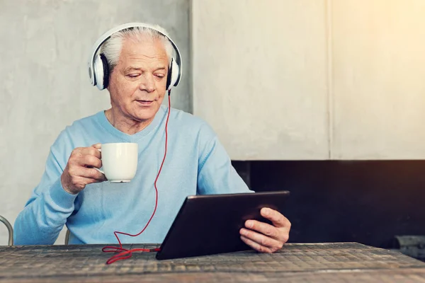 Avslappnad pensionär titta på videor och dricka te — Stockfoto