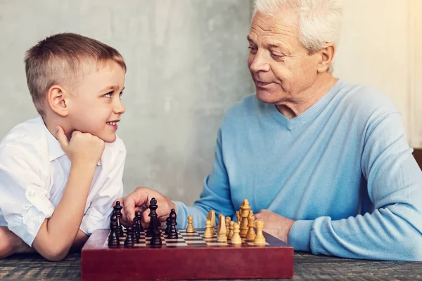 Uomo gentile guardando il ragazzo mentre gioca a scacchi — Foto Stock