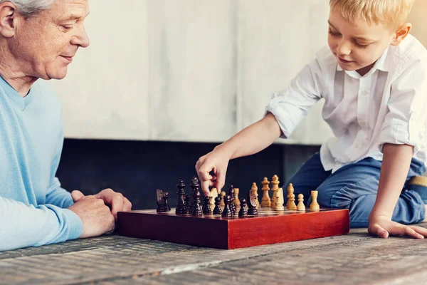 Liten pojke sitter på bord när du spelar schack — Stockfoto