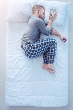 Çalar saat uyku sırasında yorgun adam