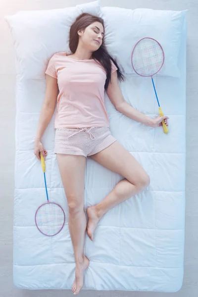 Радостная брюнетка спит с ракетками бадминтона — стоковое фото