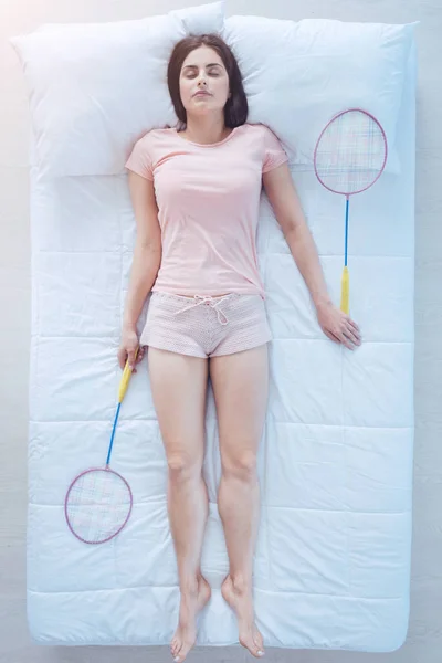 Exhausted young lady having rest with badminton rackets — Stock Photo, Image