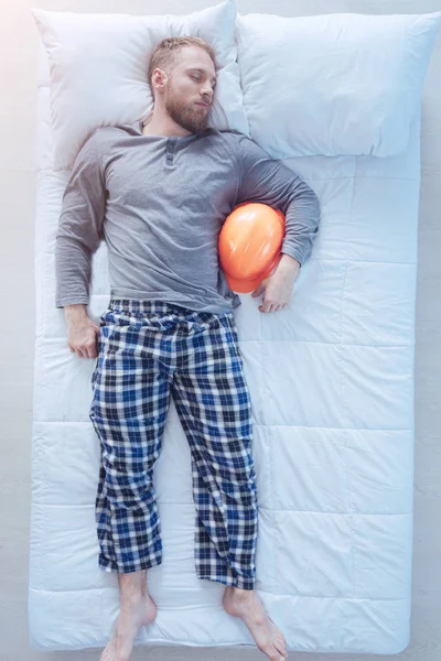 Millennial builder sleeping with hard head in bed — Stock Photo, Image