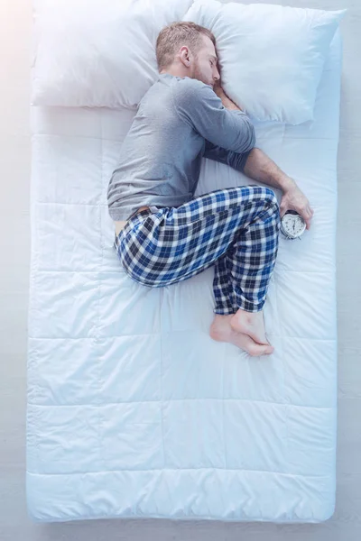 Hombre con despertador durmiendo en posición fetal —  Fotos de Stock