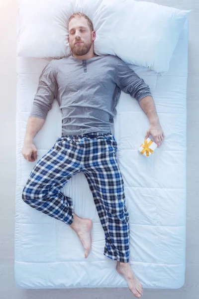 Sporty guy sleeping with gift box in hand — Stock Photo, Image