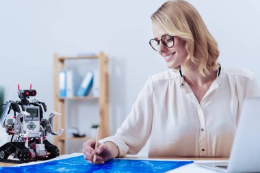 Bir robot plan üzerinde çalışan neşeli akıllı kadın