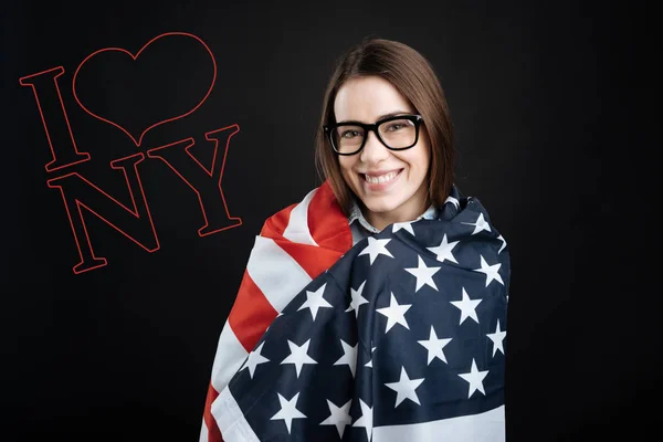 Vacker kvinna rullande själv upp Usa flaggan och ser glad — Stockfoto