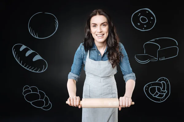 Vrolijke kok glimlachen tijdens het gebruik van een deegroller voor bakkerij — Stockfoto