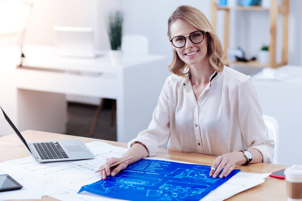 Cheerful positive woman working with a blueprint