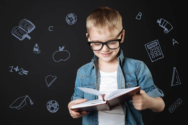 Clever schoolboy smiling while reading a book — Stock Image Clever schoolboy smiling while reading a book Royalty Free Stock Images