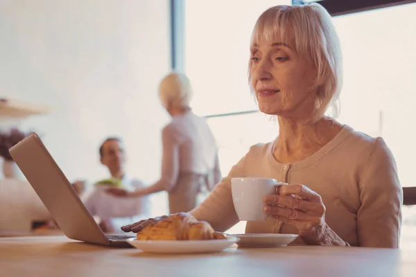 Чарівна старша леді читає пошту під час пиття кави — стокове фото