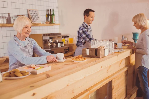 Optimistická baristas podávat kávu a croissanty pro zákazníky — Stock fotografie