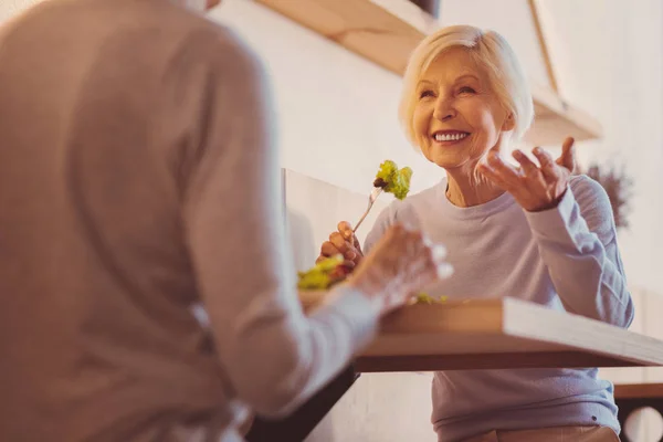 Счастливая пожилая женщина делится историями со своим другом в кафе — стоковое фото