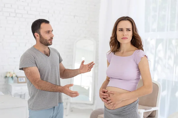 Sad man and pregnant woman arguing