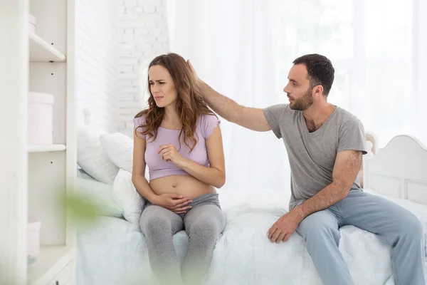 Приятный мужчина успокаивает беременную женщину — стоковое фото