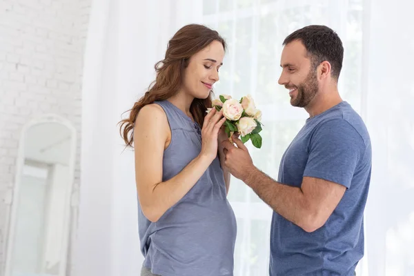 Радостный мужчина дарит цветы беременной женщине — стоковое фото