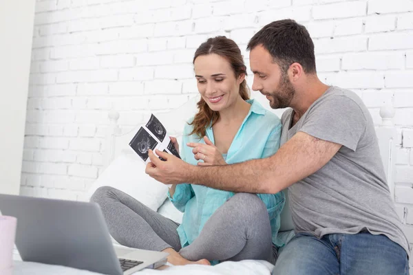 Счастливая беременная женщина и мужчина изучают ультразвук — стоковое фото
