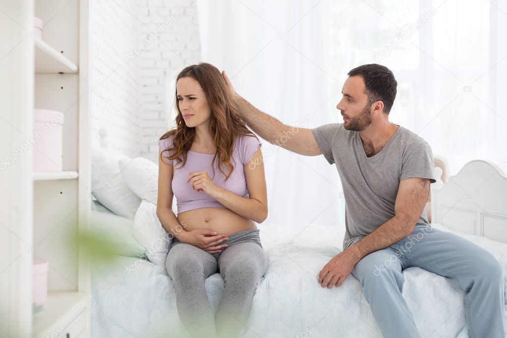 Pleasant man calming pregnant woman
