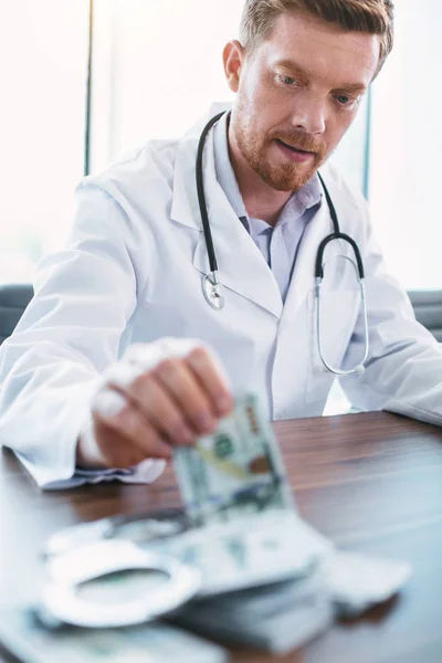 Médico sério recebendo subornos em seu escritório — Fotografia de Stock