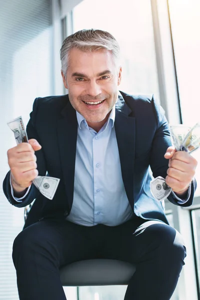 I am lucky. Joyful handsome man smiling and holding a lot of money