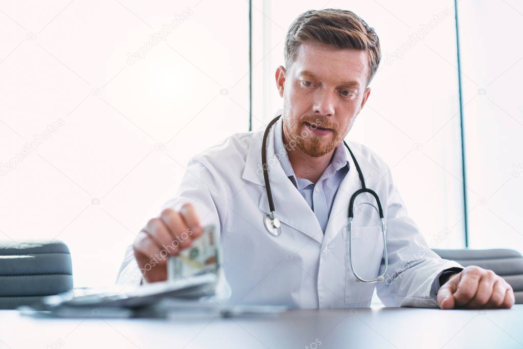 Successful doctor taking bribes in his office
