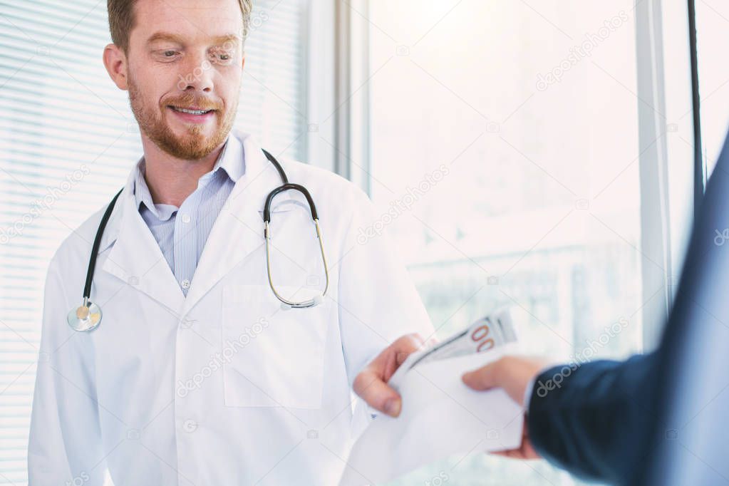 Smiling doctor taking a substantial bribe