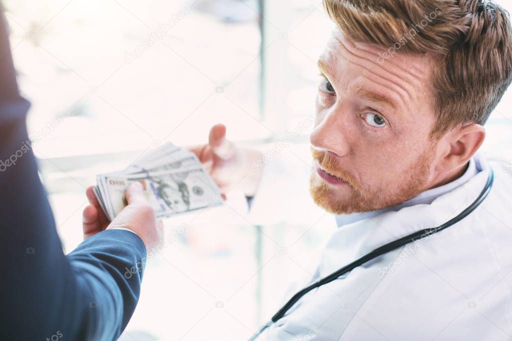 Unjust doctor taking a bribe for operation