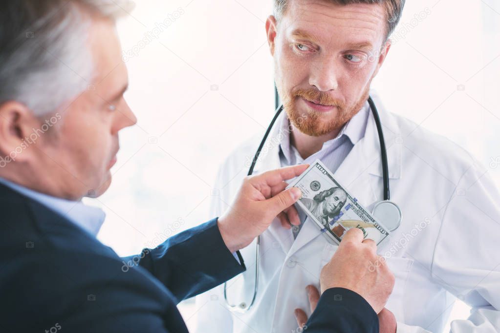 Delighted dishonest doctor taking a bribe