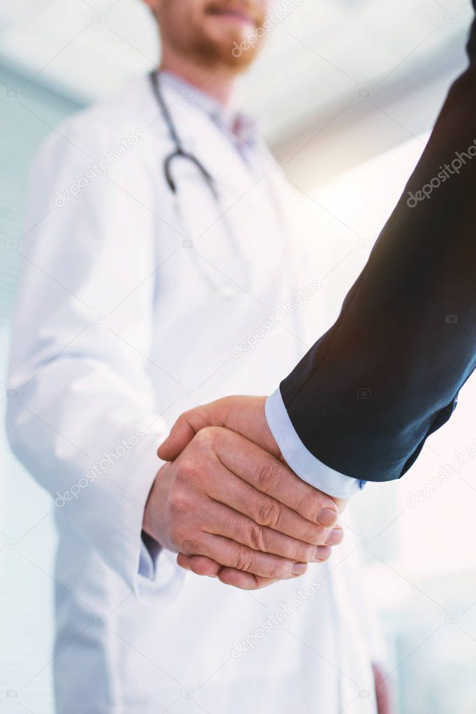 Happy doctor shaking hands with a businessman
