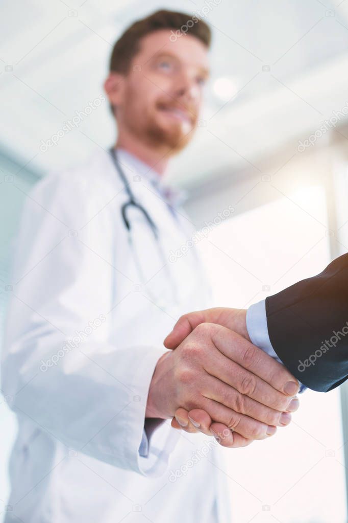 Inspired doctor shaking hands with a businessman