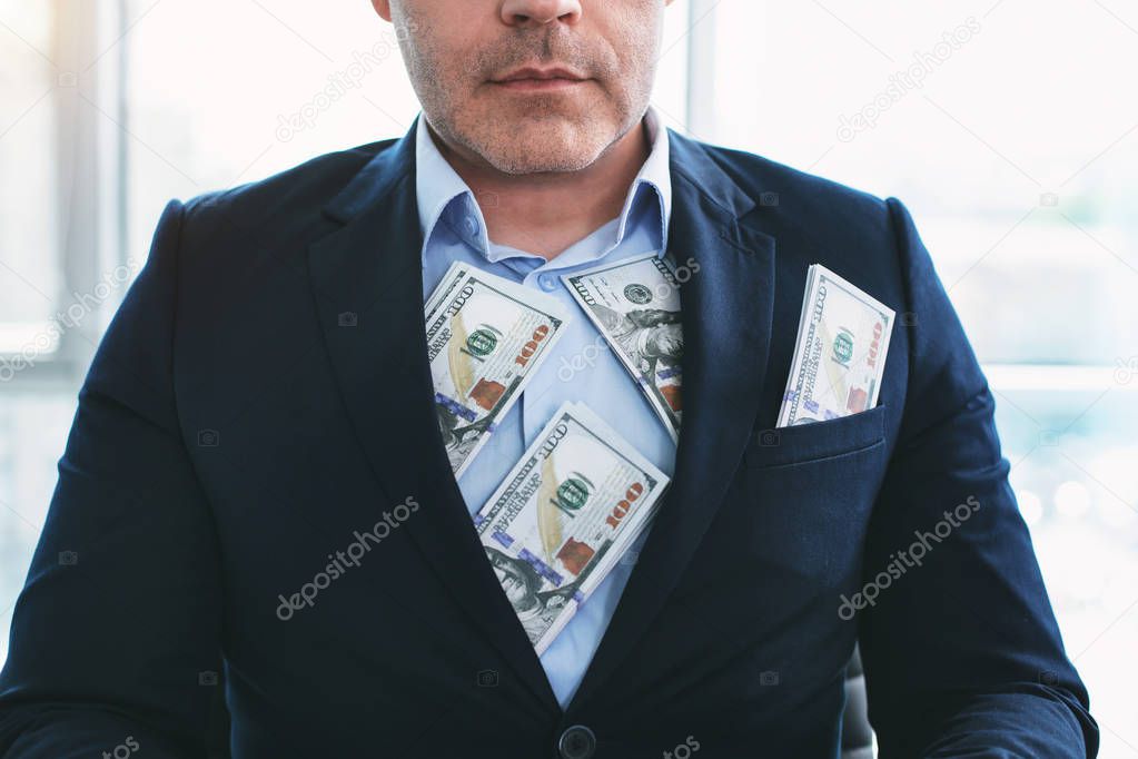 I am greedy. Concentrated scrooge businessman wearing a suit and having a lot of money
