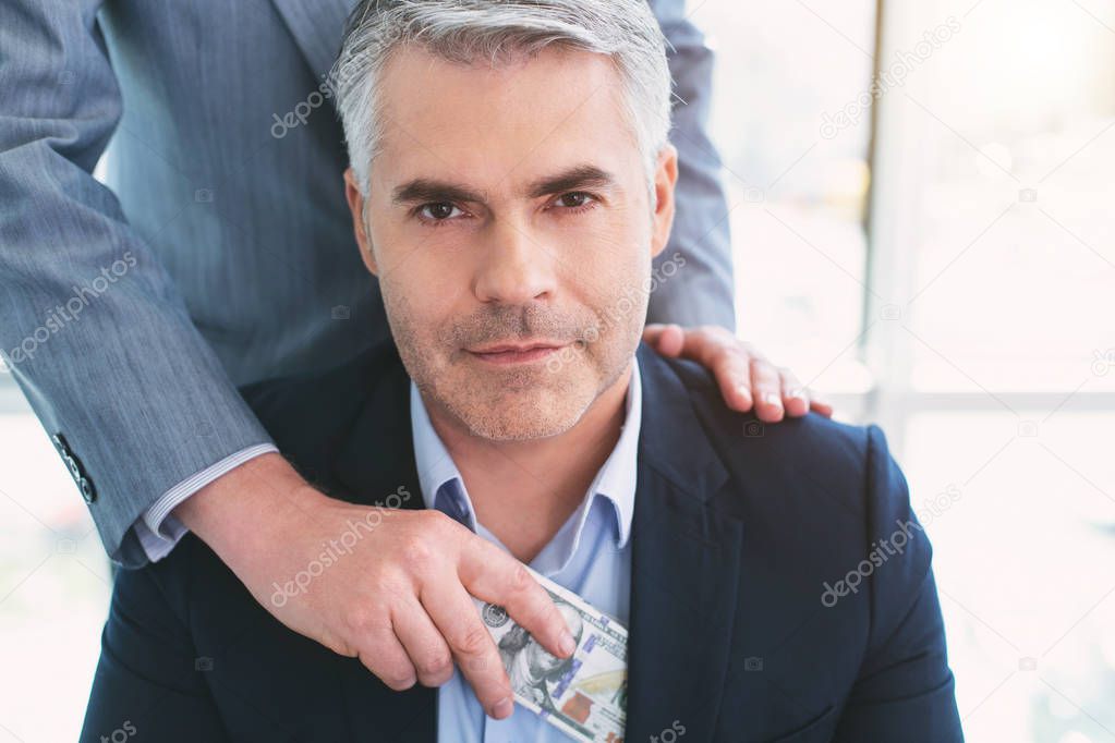 Inspired dark-eyed businessman taking a bribe