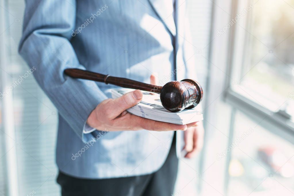 Greedy official holding money and inscribed gavel