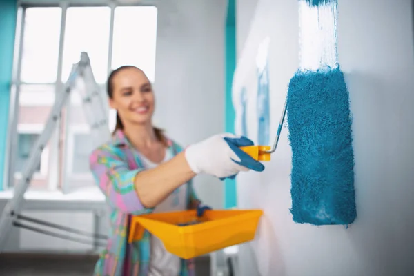 Mujer alegre sosteniendo un rodillo y pintando — Foto de Stock